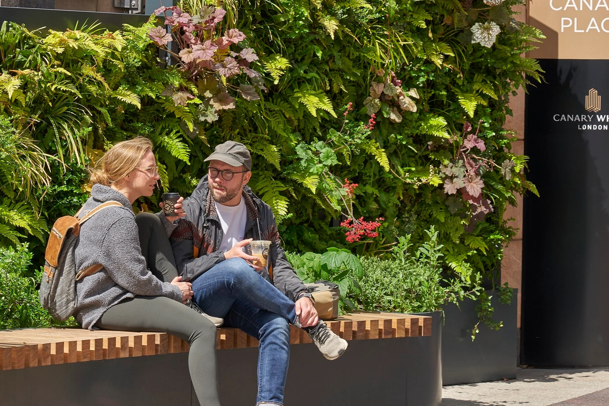 People sitting beside an outdoor living wall at Canary Wharf in London