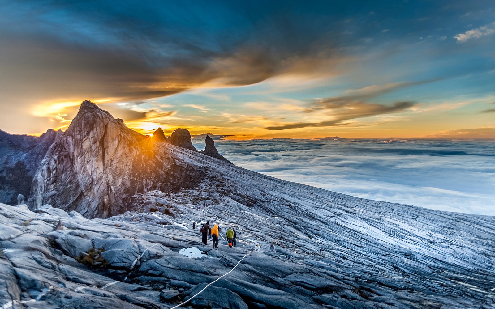 Hikers ascending Mount Kinabalu summit at sunrise, Malaysia.
