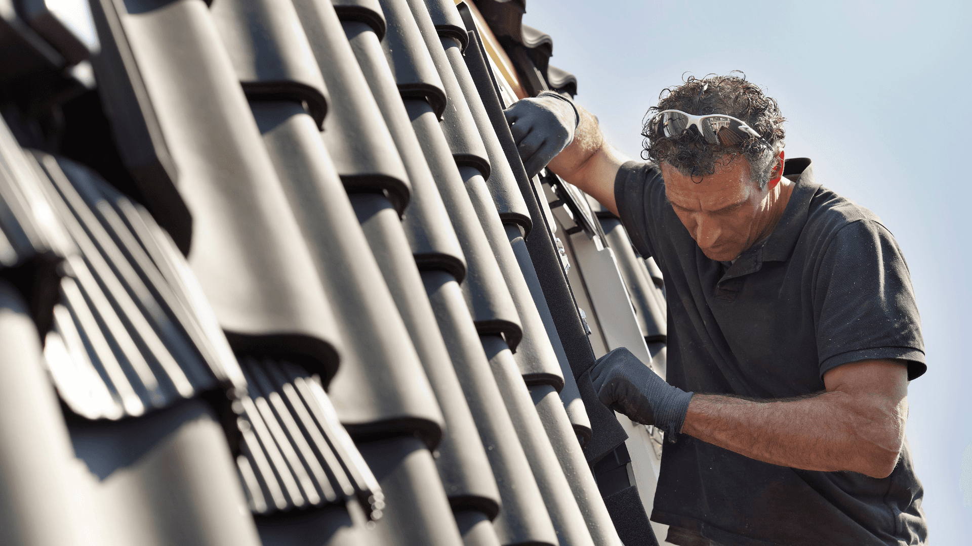 Dachdecker bei Arbeiten auf einem Dach mit Werkzeug. Silhouette vor blauem Hintergrund und orangefarbener Fläche.