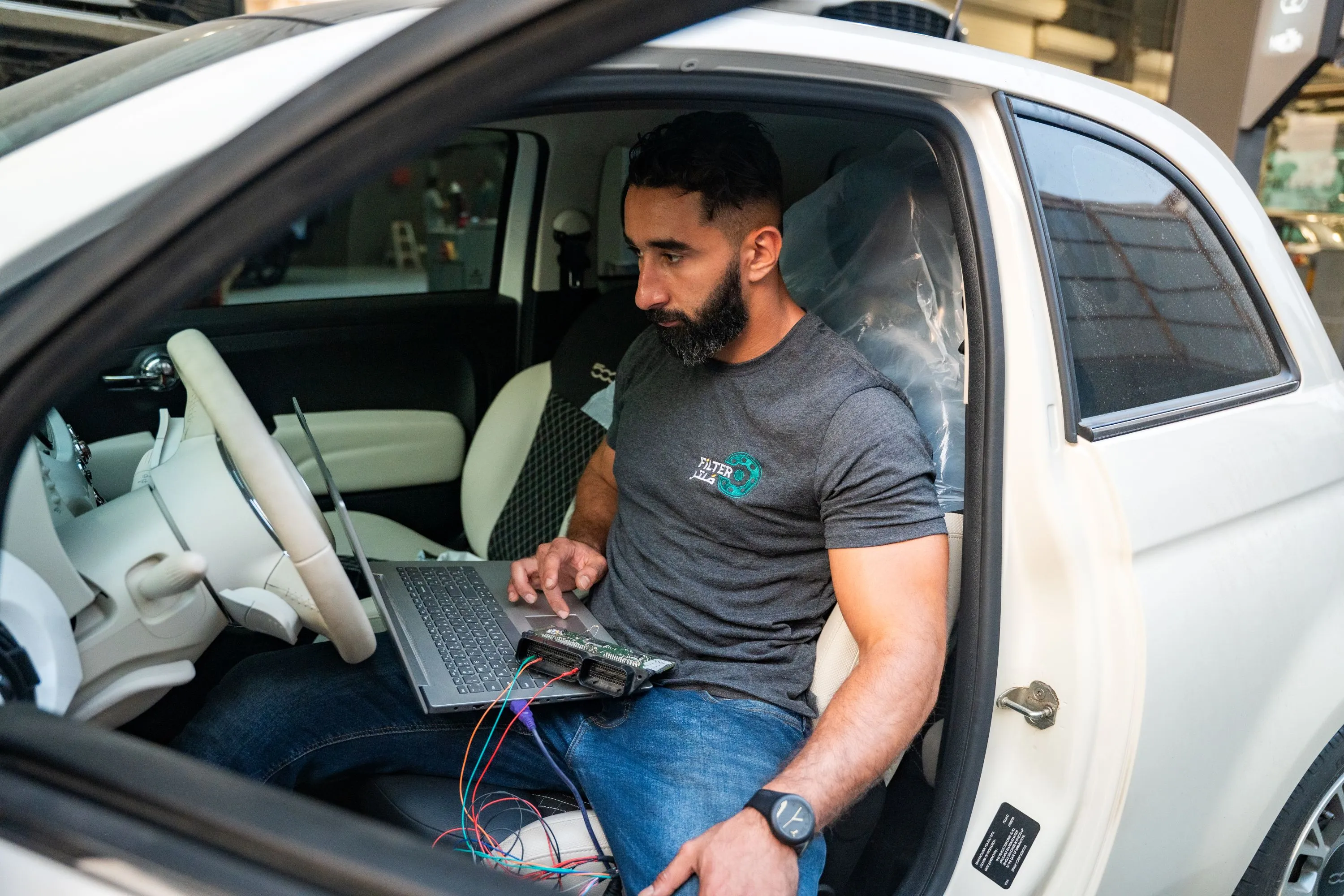 شخص يحمل جهاز لوحي مع تطبيق تشخيص محرك السيارة أمام غطاء السيارة.