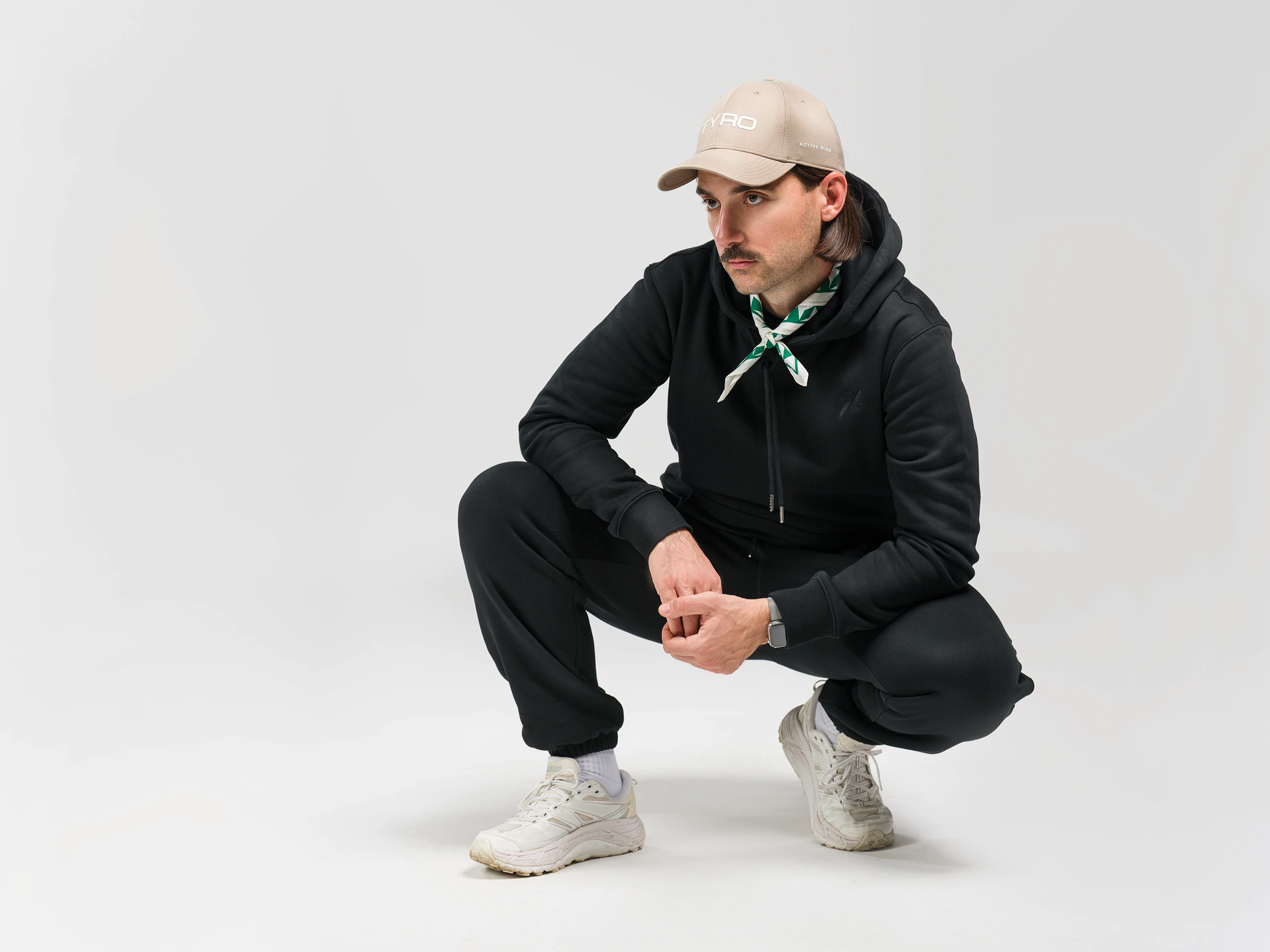 Man in sportswear squatting in a studio on a light background.
