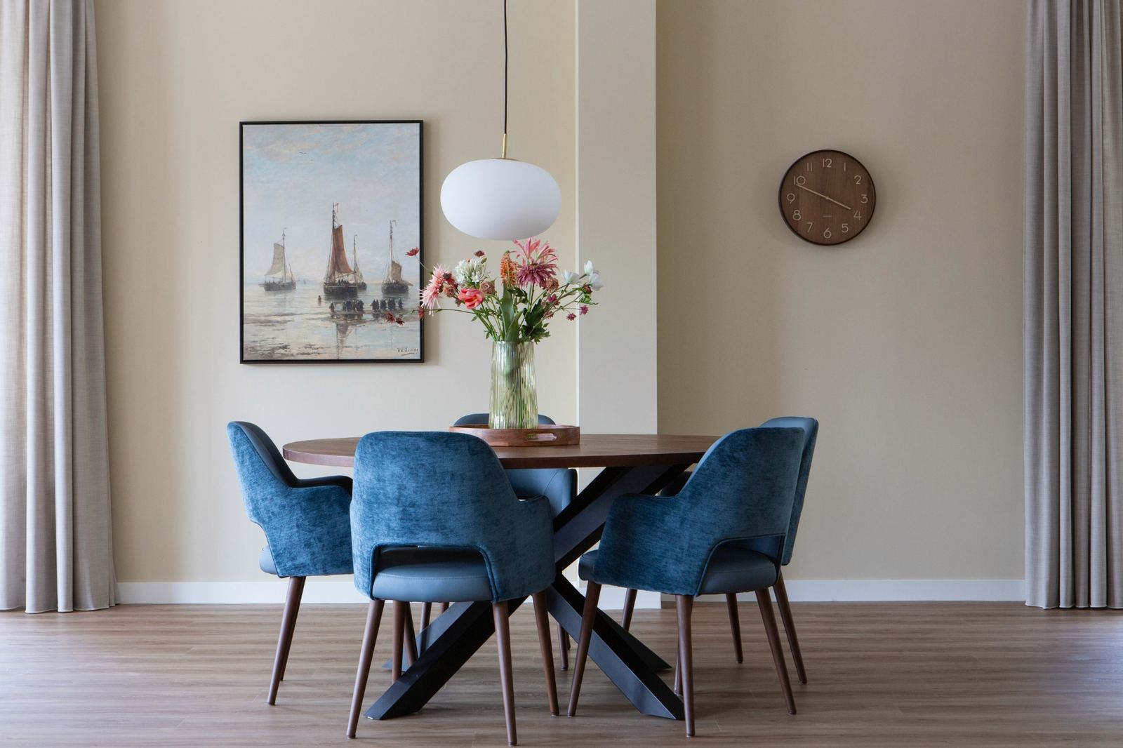 ronde tafel met blauwe stoelen en klassiek schilderij