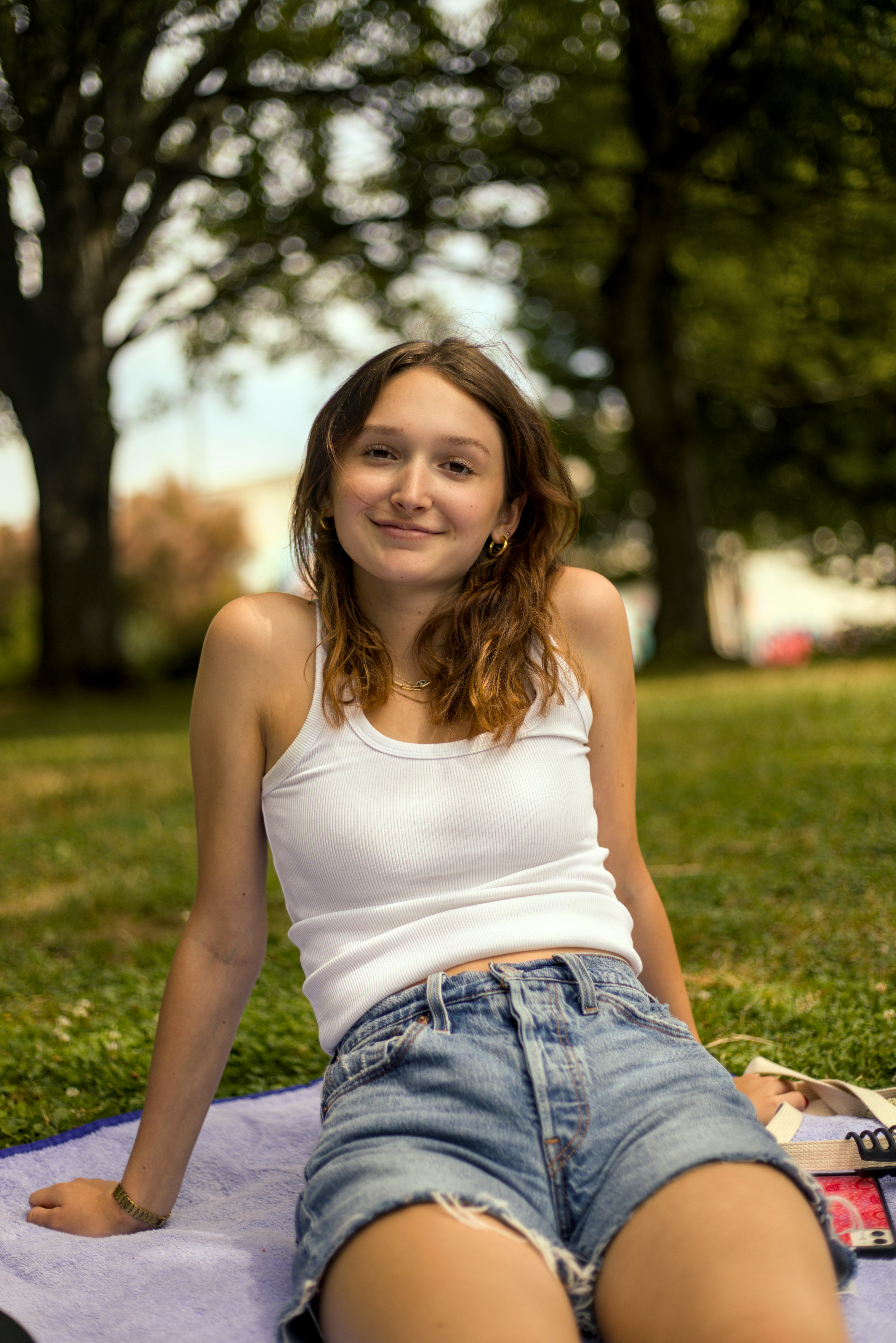 a woman sitting on a towel in a park