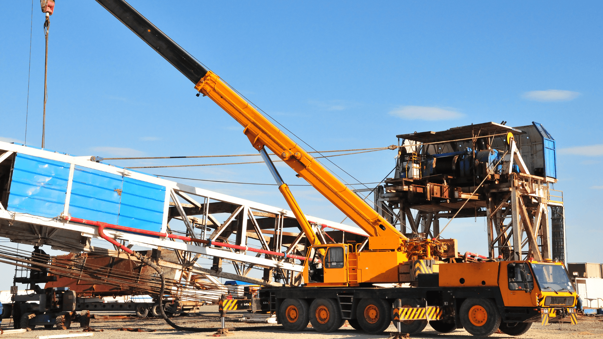 Large yellow mobile crane set up for a heavy lift rigging operation at an industrial site.