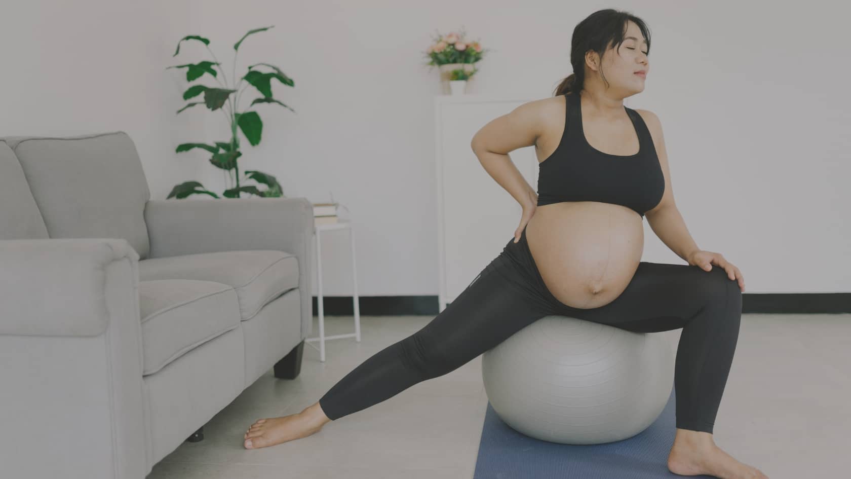 Femme enceinte réalisant un exercice de stretching avec un ballon de Pilates pour soulager les maux de grossesse.