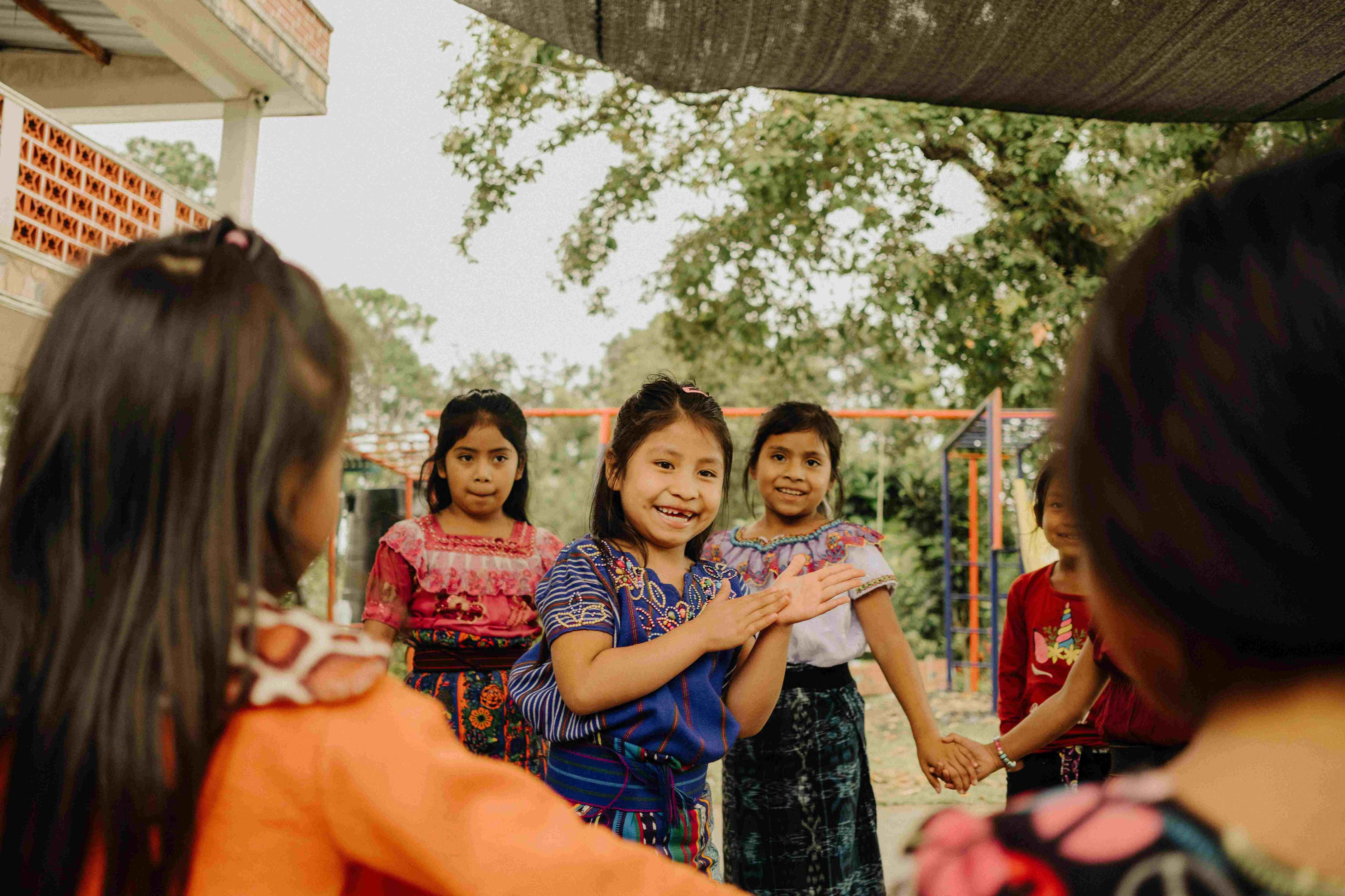 Smiling young girls embrace and laugh together outdoors, reflecting the joy and community fostered by faith-based care.