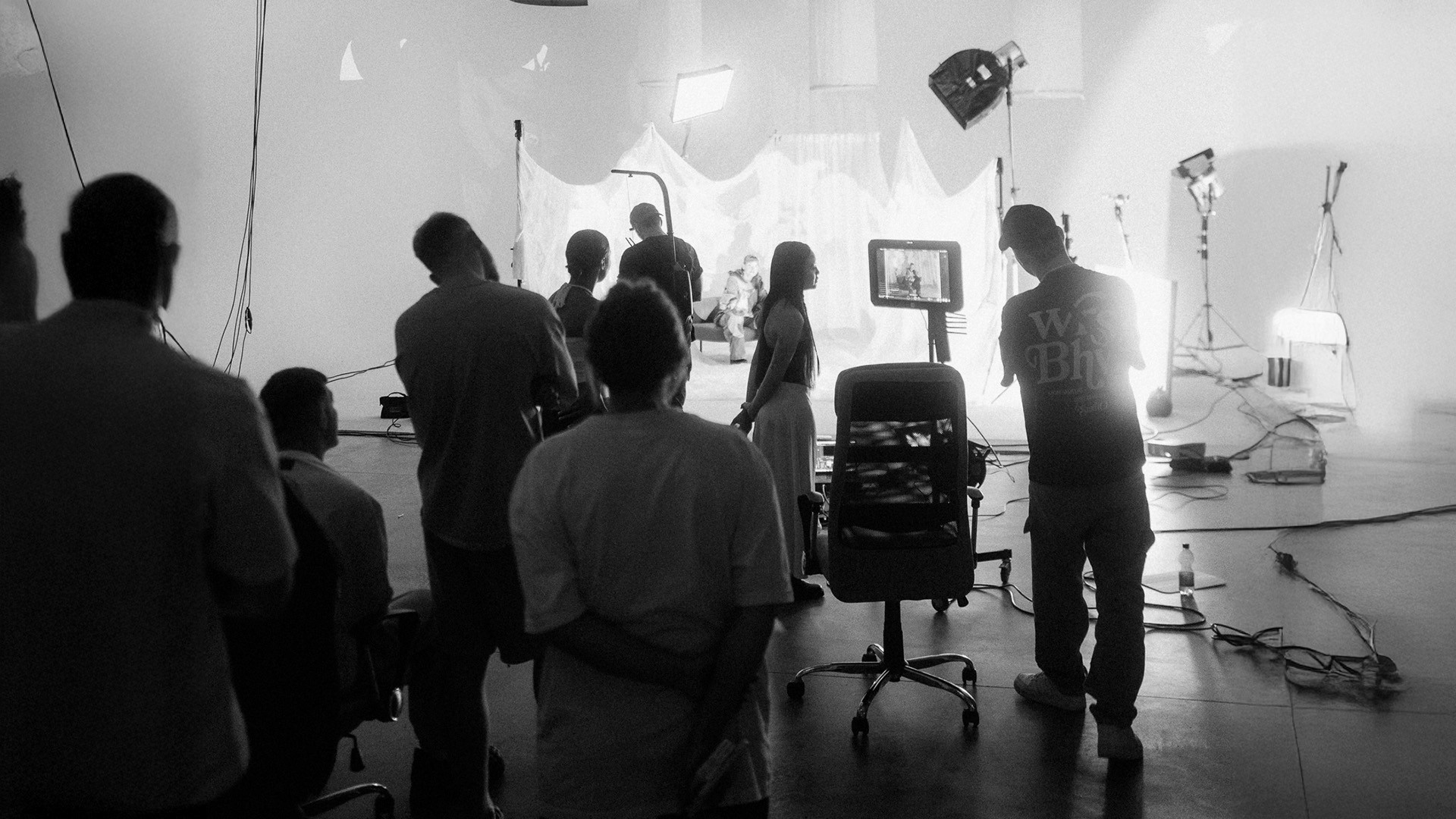 black and white image, people working on a movie set for a musicvideo lights and monitor in studio