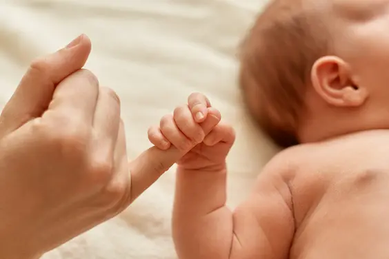 bébé tenant le doigt de sa maman