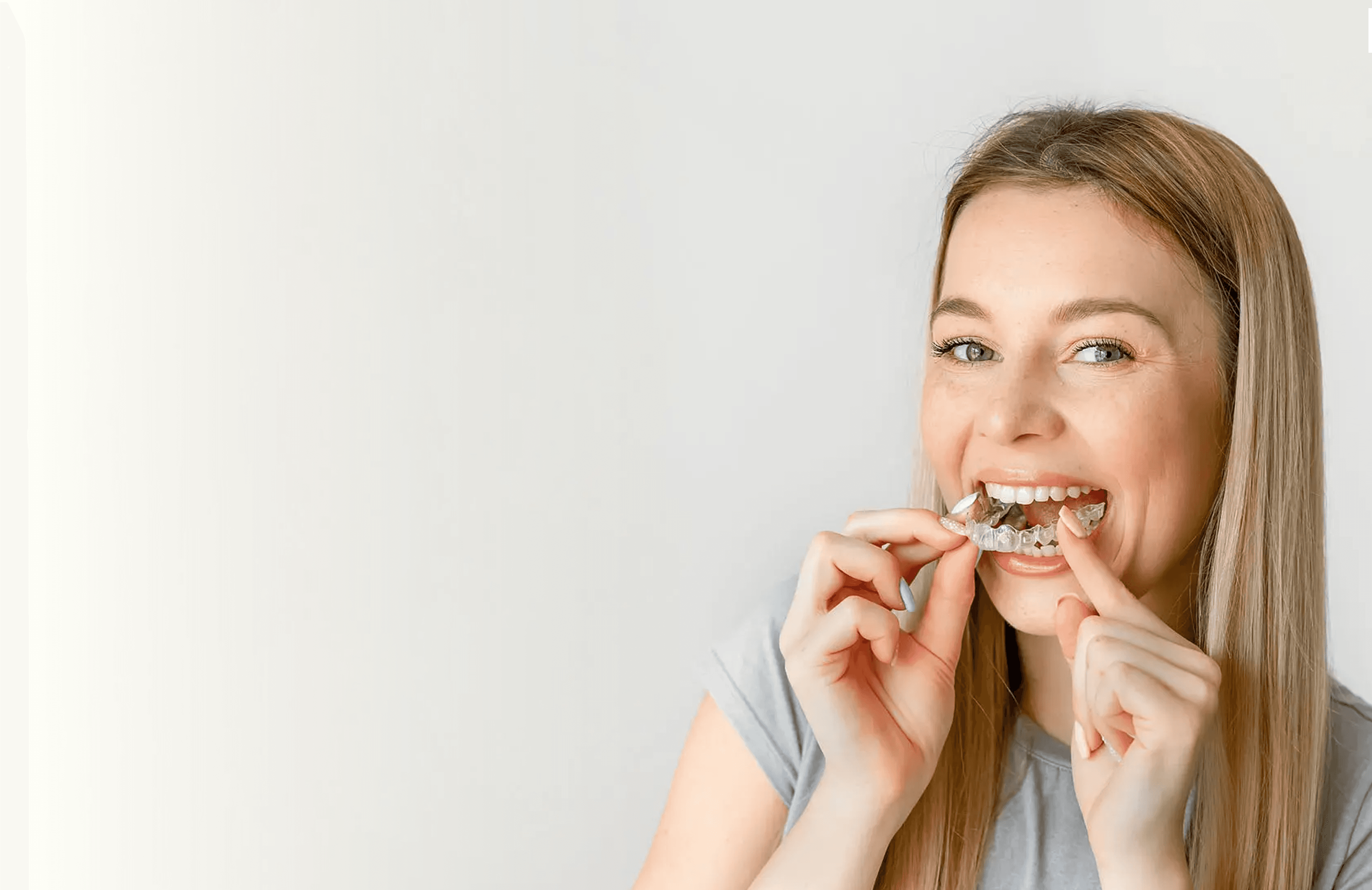 A woman smiles and holds invisalign clear aligners with a case, showcasing a certified invisalign provider at Bella Medical Centre
