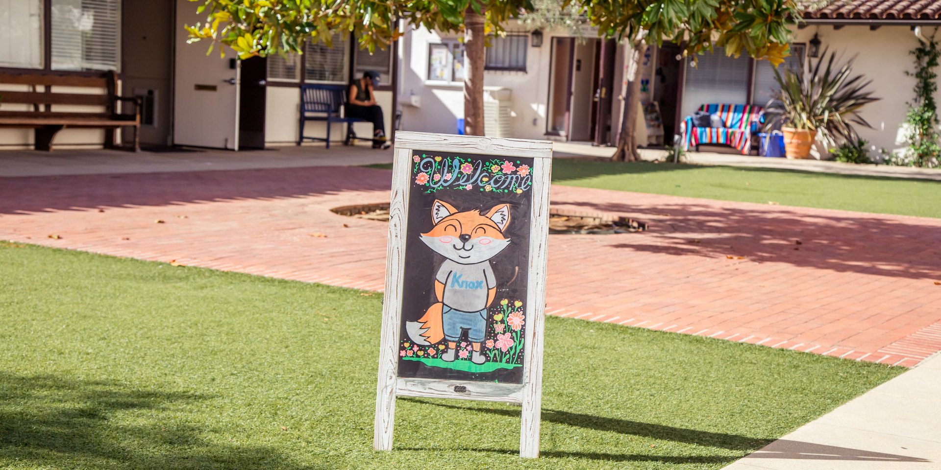 Welcome chalkboard sign with the Knox fox mascot standing on the courtyard lawn