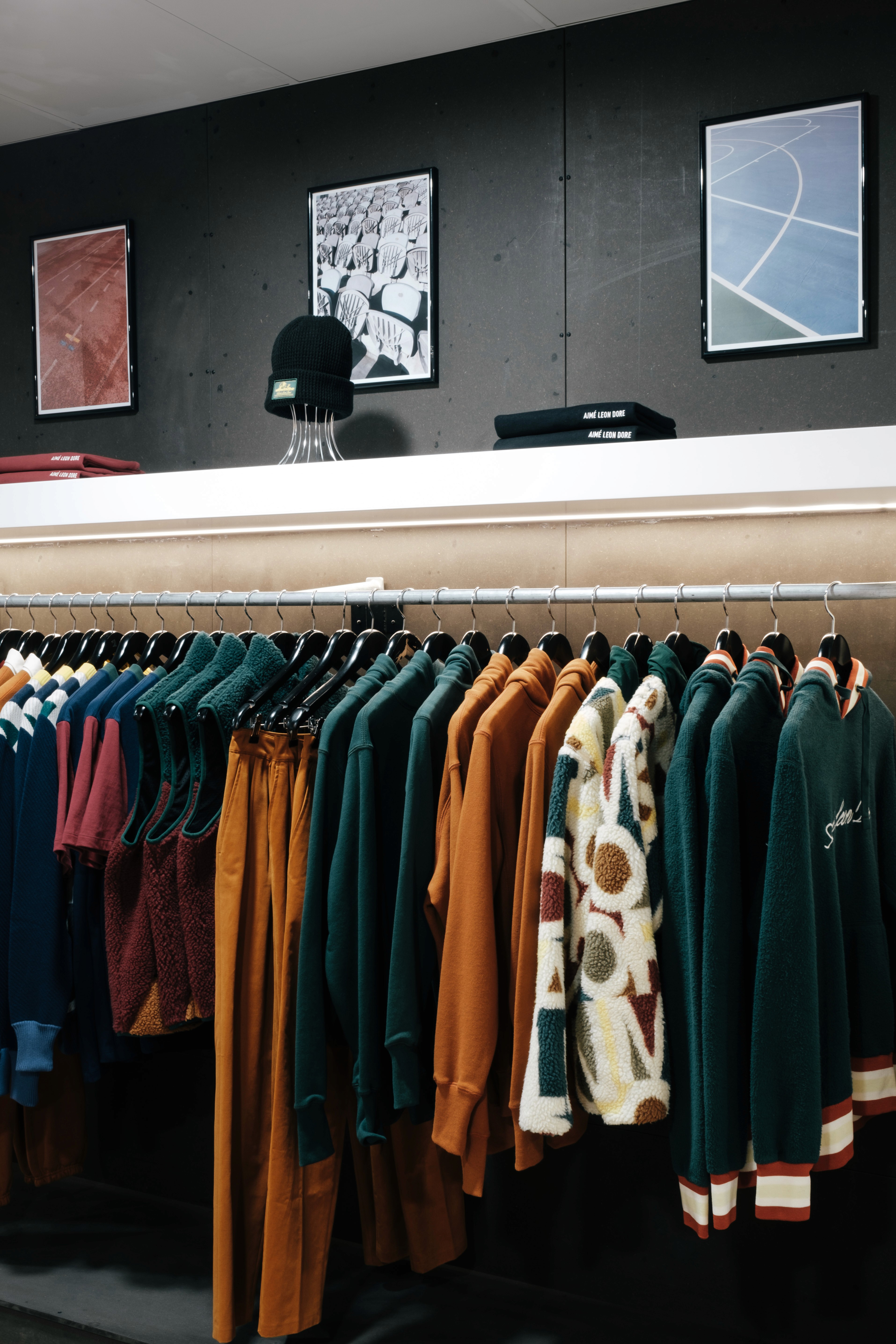 Apparel display inside Double Double, showing a curated rack of jackets and knitwear beneath framed graphic prints.