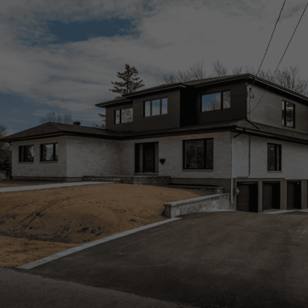 Newly renovated modern two-story home with a grey brick exterior, dark upper cladding, black framed windows, and a fresh driveway—part of B&Y Reno Corp’s residential transformation projects.
