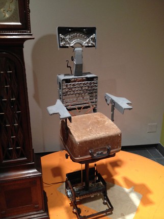 installation view of a sculpture made with a handbag, and other metal pieces