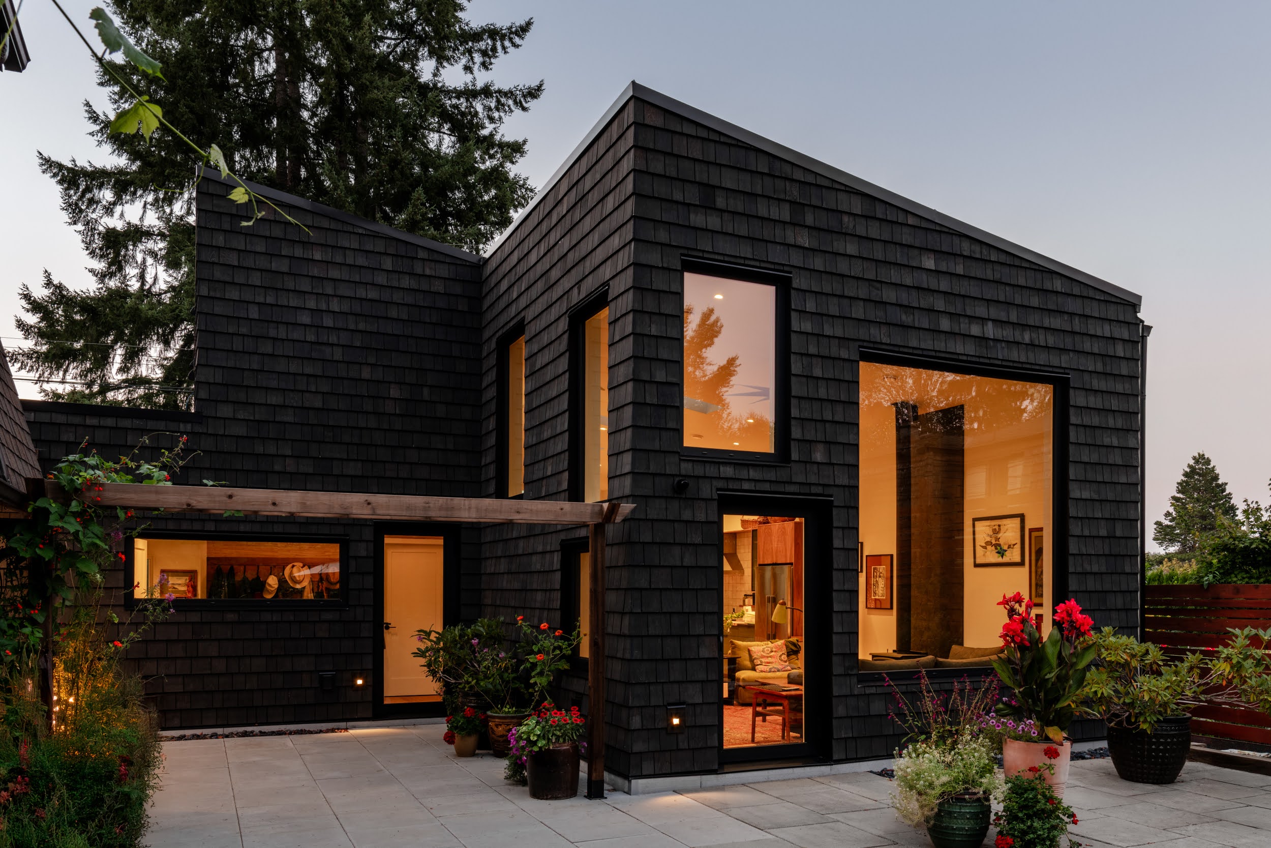 Modern indoor space with large glass doors, lush greenery, and a cozy seating area visible beyond.