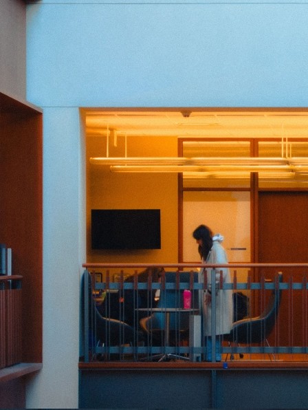 People talking in a warmly lit office lounge seen through glass behind a railing, illustrating quality of earnings analysis.
