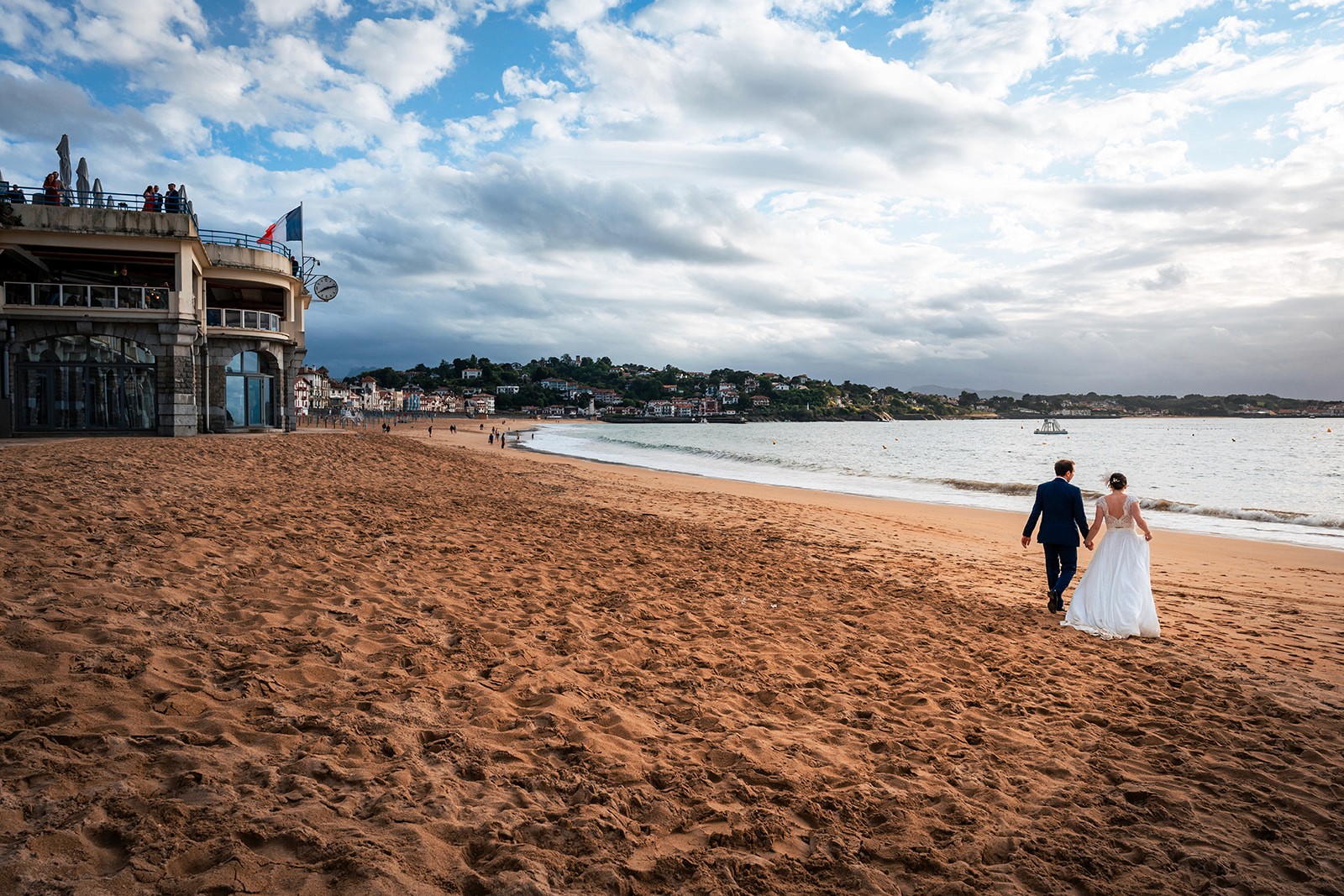le couple de mariés marche sur la plage devant l'hotel thalazur à saint jean de luz au pays basque