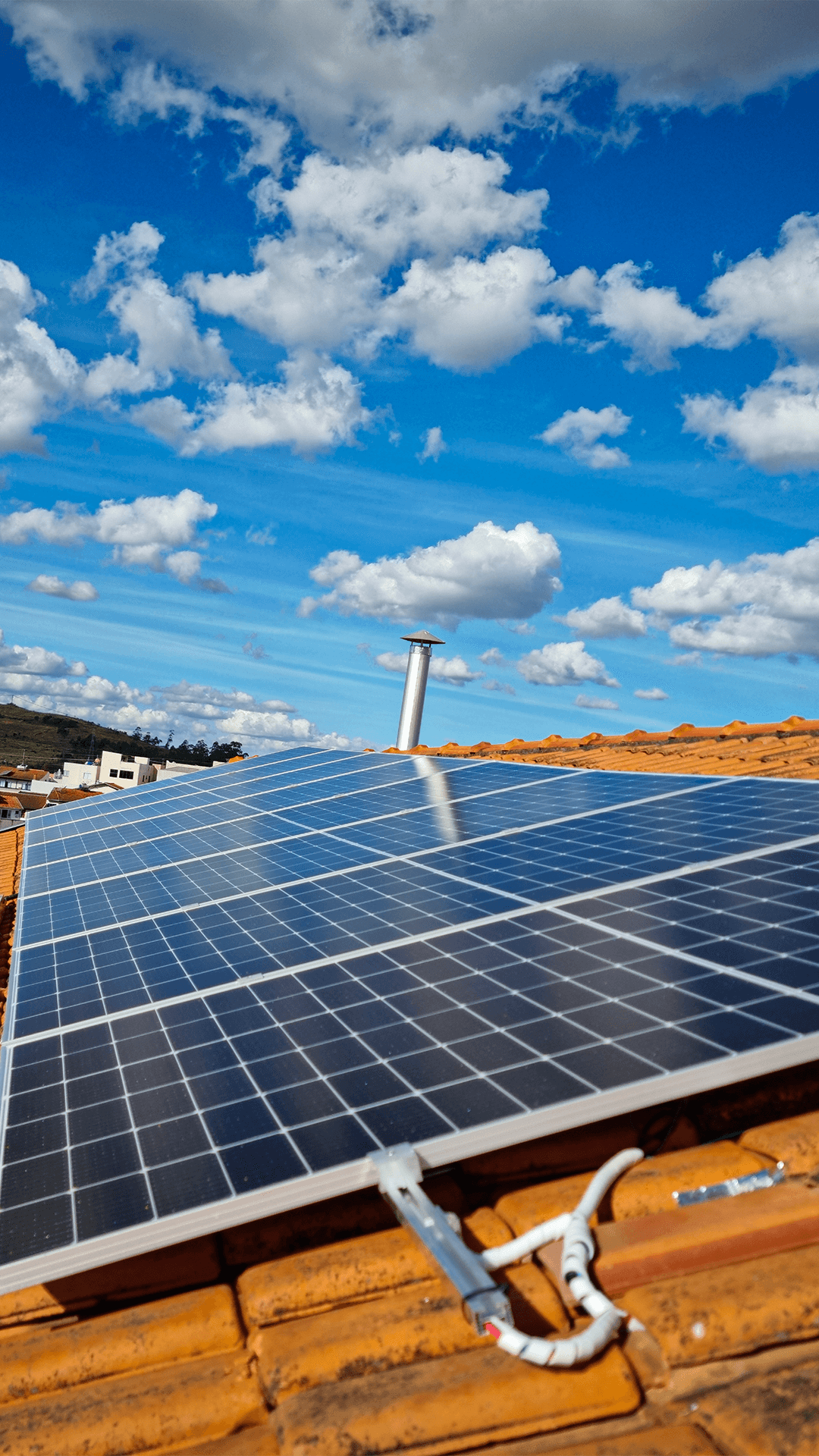 A smiling young man with crossed arms, wearing a plaid shirt and white t-shirt, poses against a dark background.