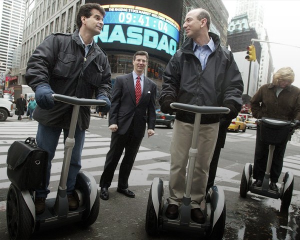 Jeff Bezos and other early dot com CEOs shown riding Segway scooters in front of the NASDAQ building