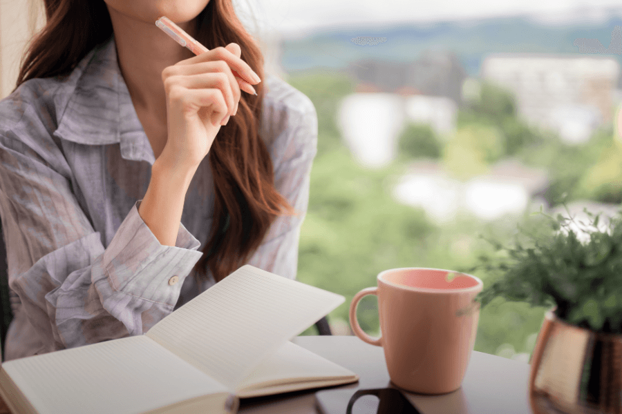 woman thinking with her pen above her notebook