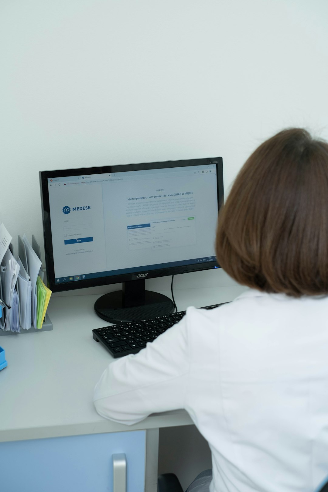 a woman sitting at a desk looking at a computer screen