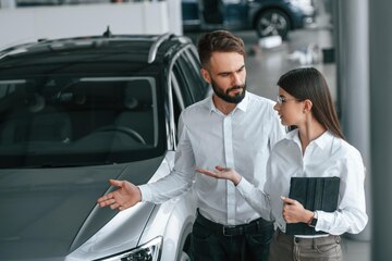 Venditore di auto e cliente che discutono di un'auto
