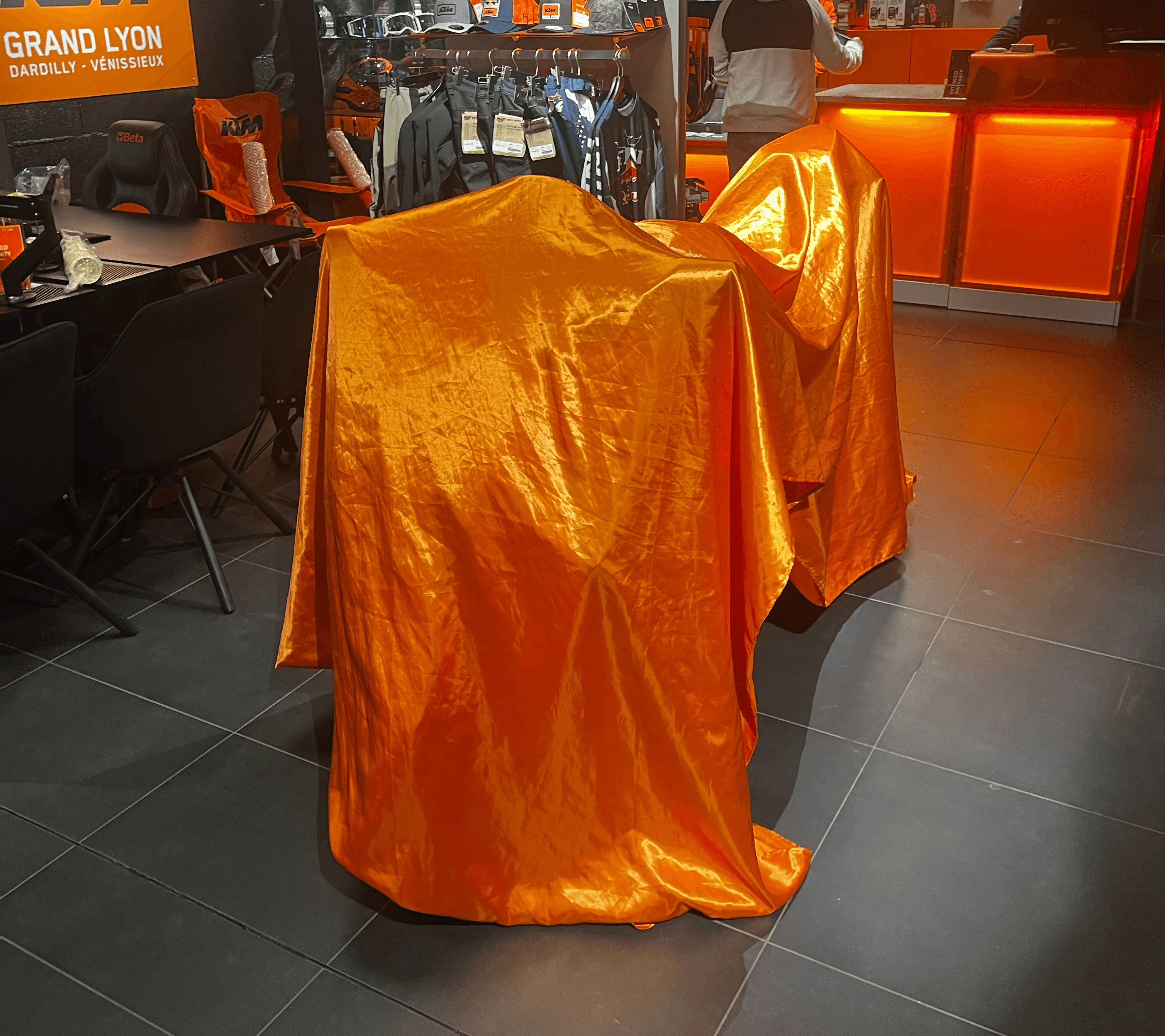 Motos KTM recouvertes sous bâche orange lors de la soirée d’inauguration chez KTM Grand Lyon