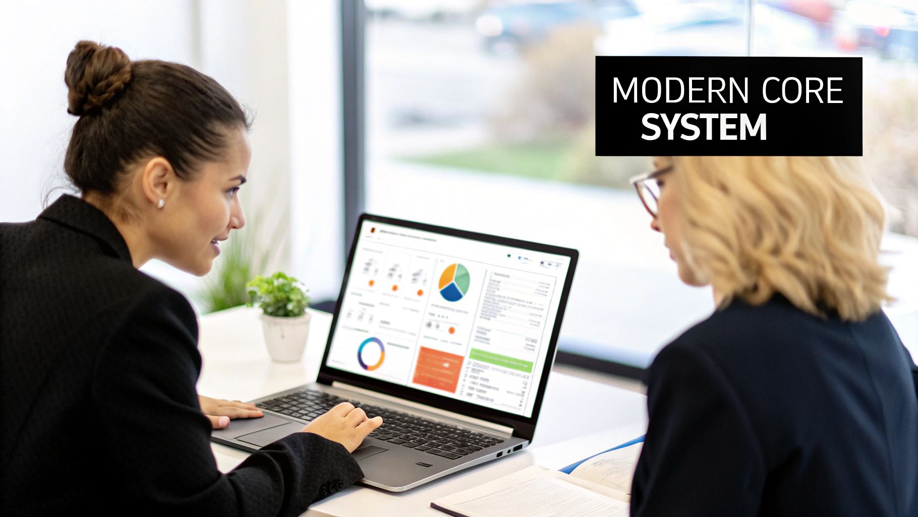 Two businesswomen analyze data on a laptop, demonstrating a modern core system in action.