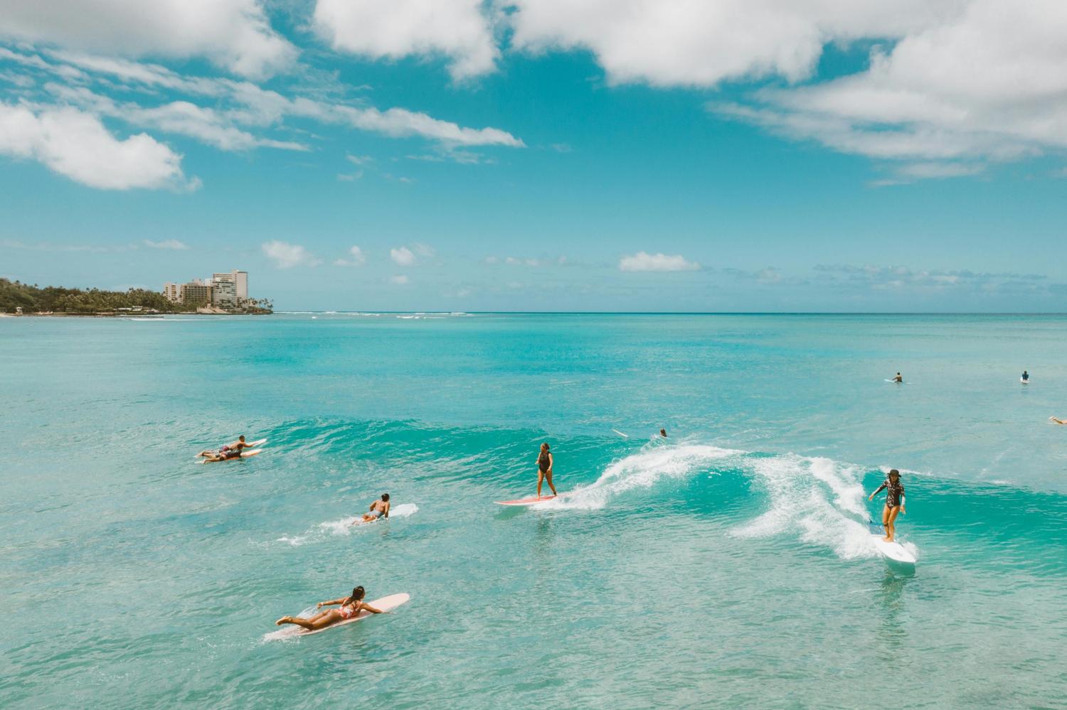 Surfers paddling in tropical turquoise water — surfboard rental in Central America