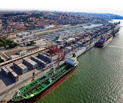 A bird's eye view of a Spanish port with shipping containers and cranes, with digital overlay graphics to signify technological integration.