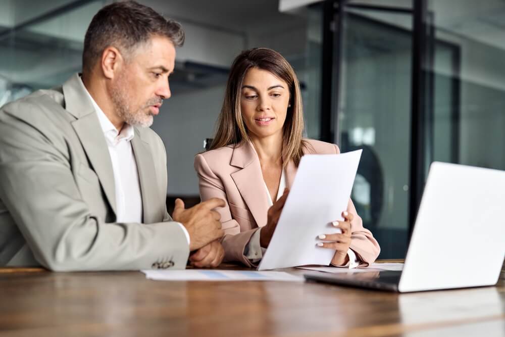 Businessman and lawyer reviewing documents together in a modern office setting. Form I539