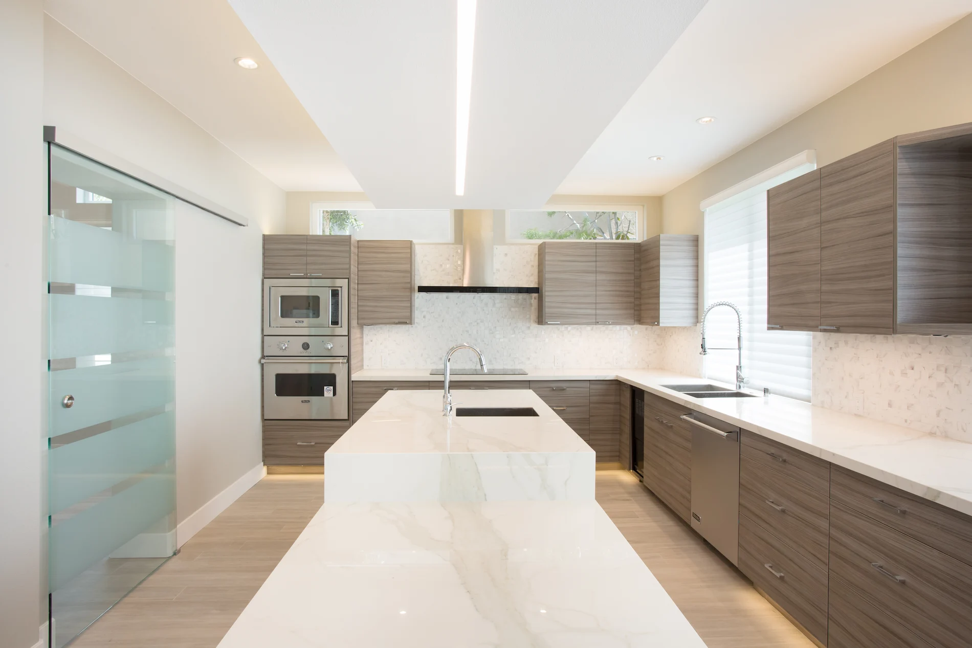 Closeup view of the kitchen over the island, showcasing the unique cabinetry veneer and porcelain countertops in this modern Harbor Cove home. Photo by Todd Huge.