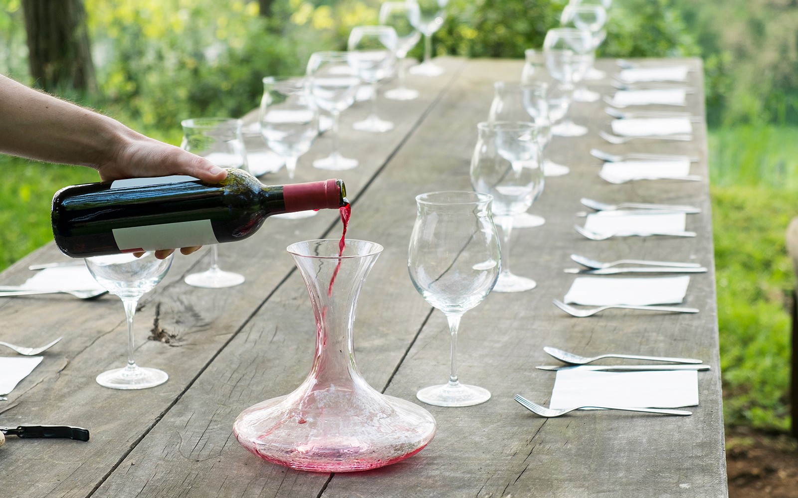 在一个为托斯卡纳葡萄酒之旅准备的乡村风格餐桌上，红酒被倒入醒酒器中。