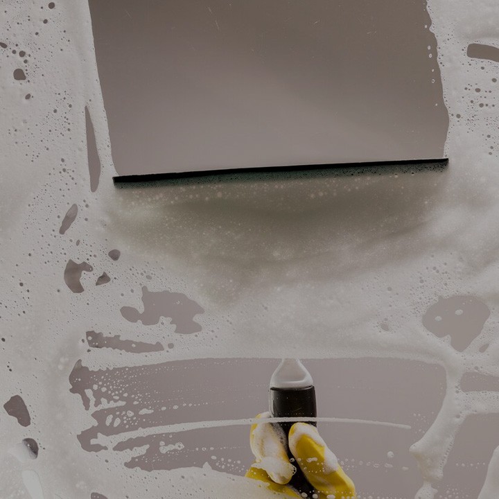 Une vitre très bien savonnée est nettoyée au centre par une raclette professionnelle