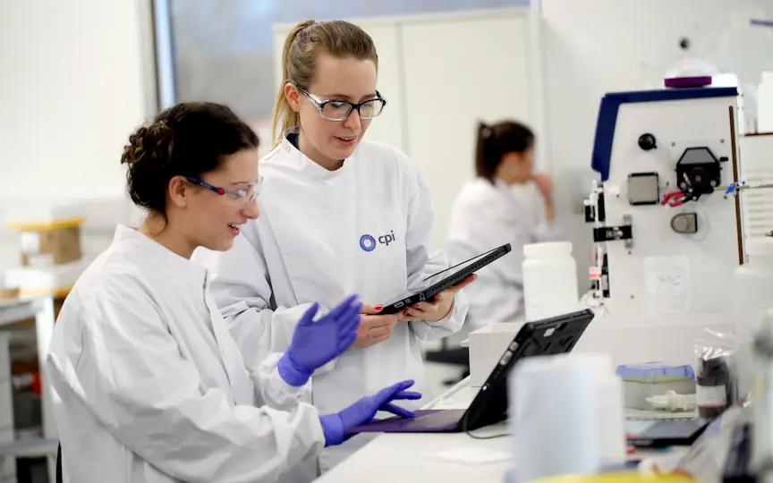 A photo of two CPI lab scientists comparing data on a laptop and smart tablet