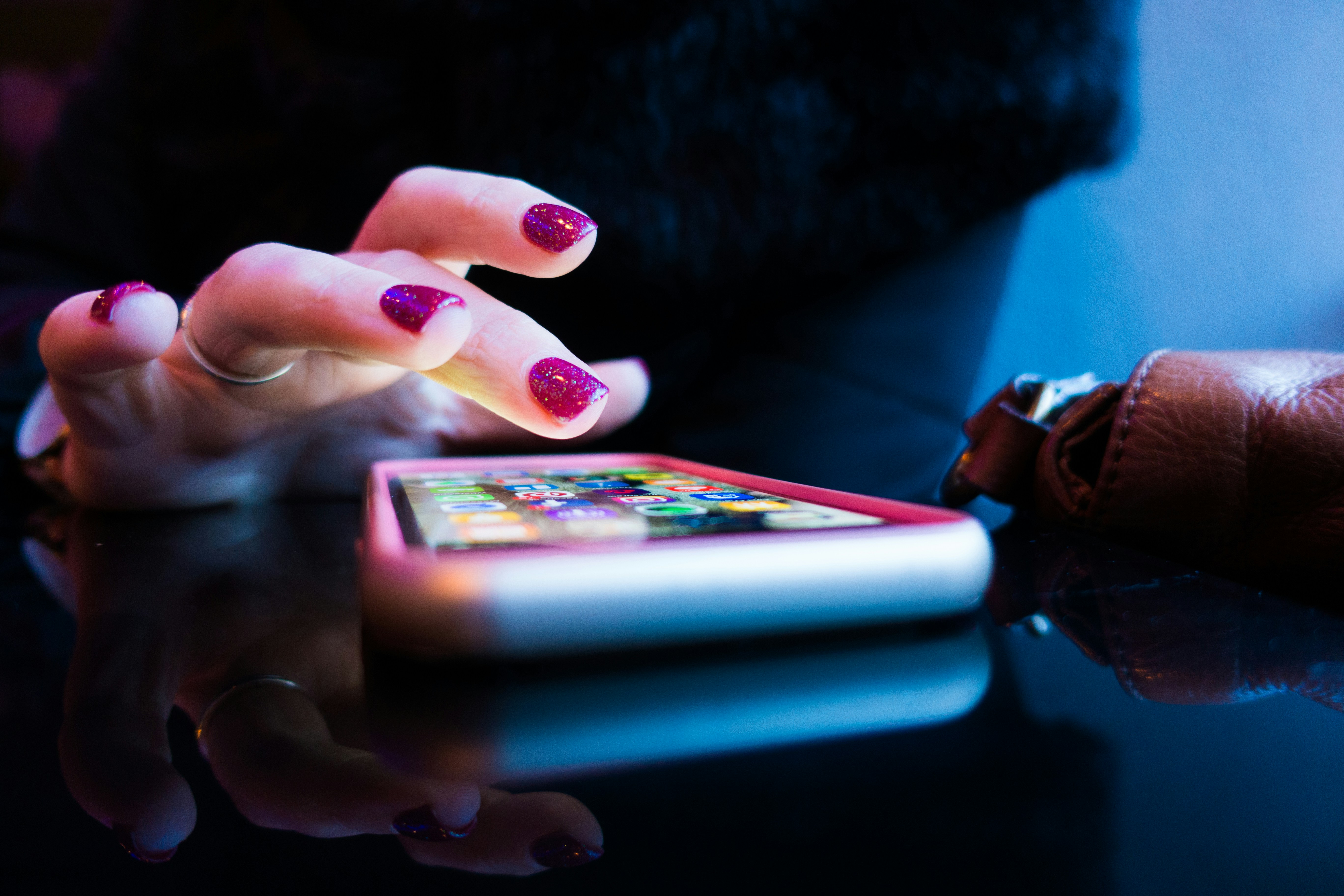 Ragazza che usa uno smartphone con lo smalto color fuxia