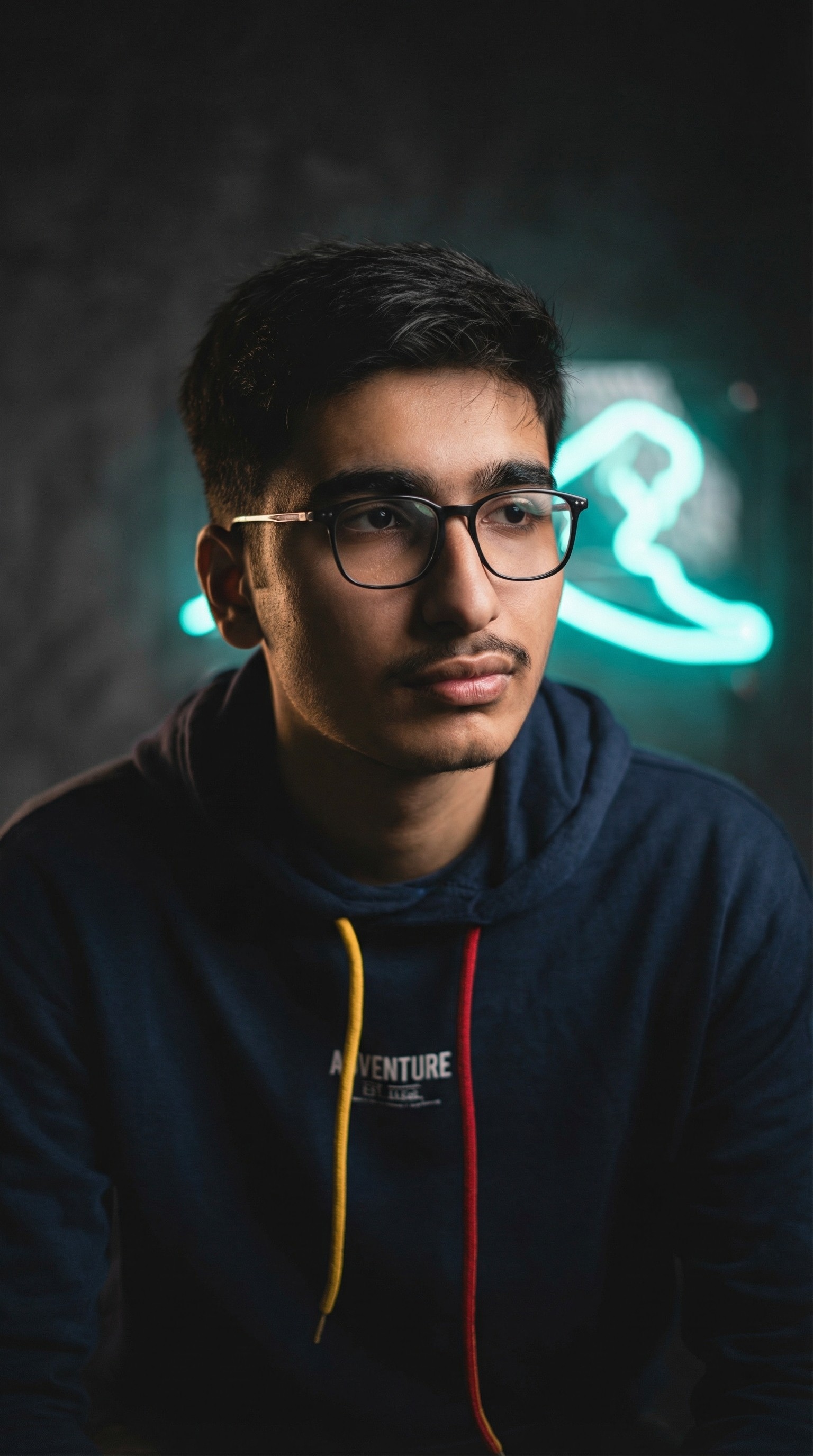 A thoughtful young person with dark hair gazes to the side, captured in soft black and white lighting.