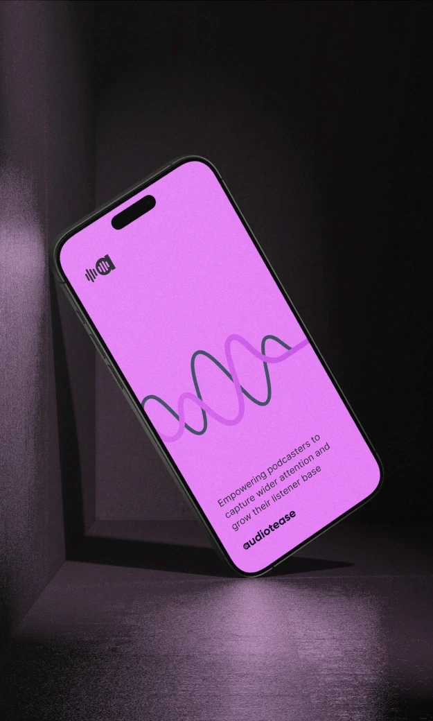 A smartphone with a bright pink screen displaying the Audiotease app, featuring a waveform graphic and the text 'Empowering podcasters to capture wider attention and grow their listener base' along with the AudioTease logo at the bottom. The phone is placed in a dark, reflective environment, highlighting the vibrant screen.