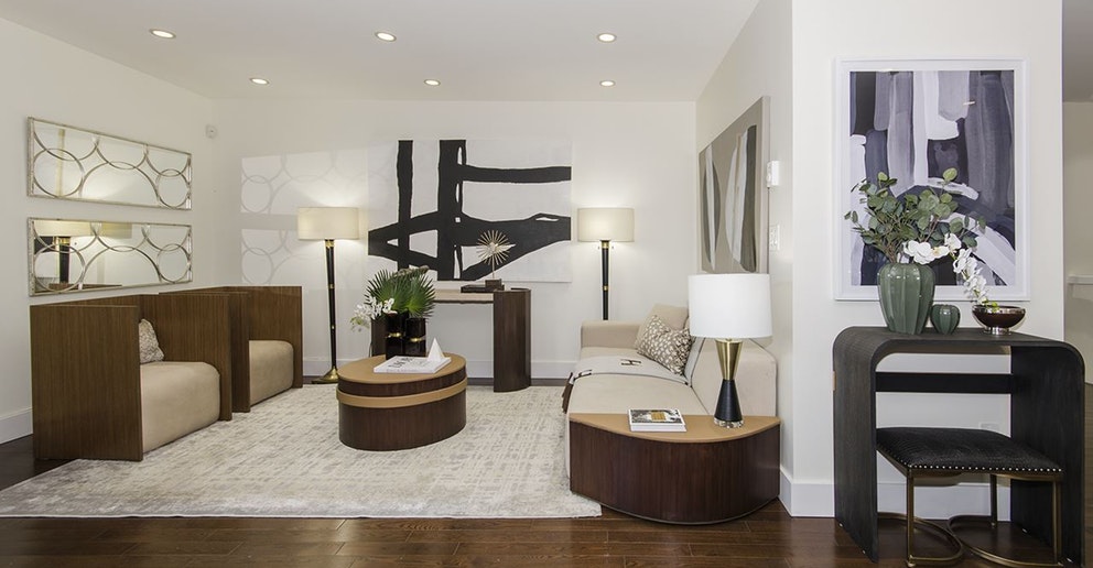 Modern living room featuring neutral tones, two armchairs, a rug, round tables, and stylish decor.