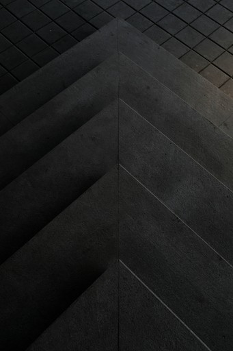 Abstract close-up of textured black surface with a herringbone pattern, creating a layered appearance.