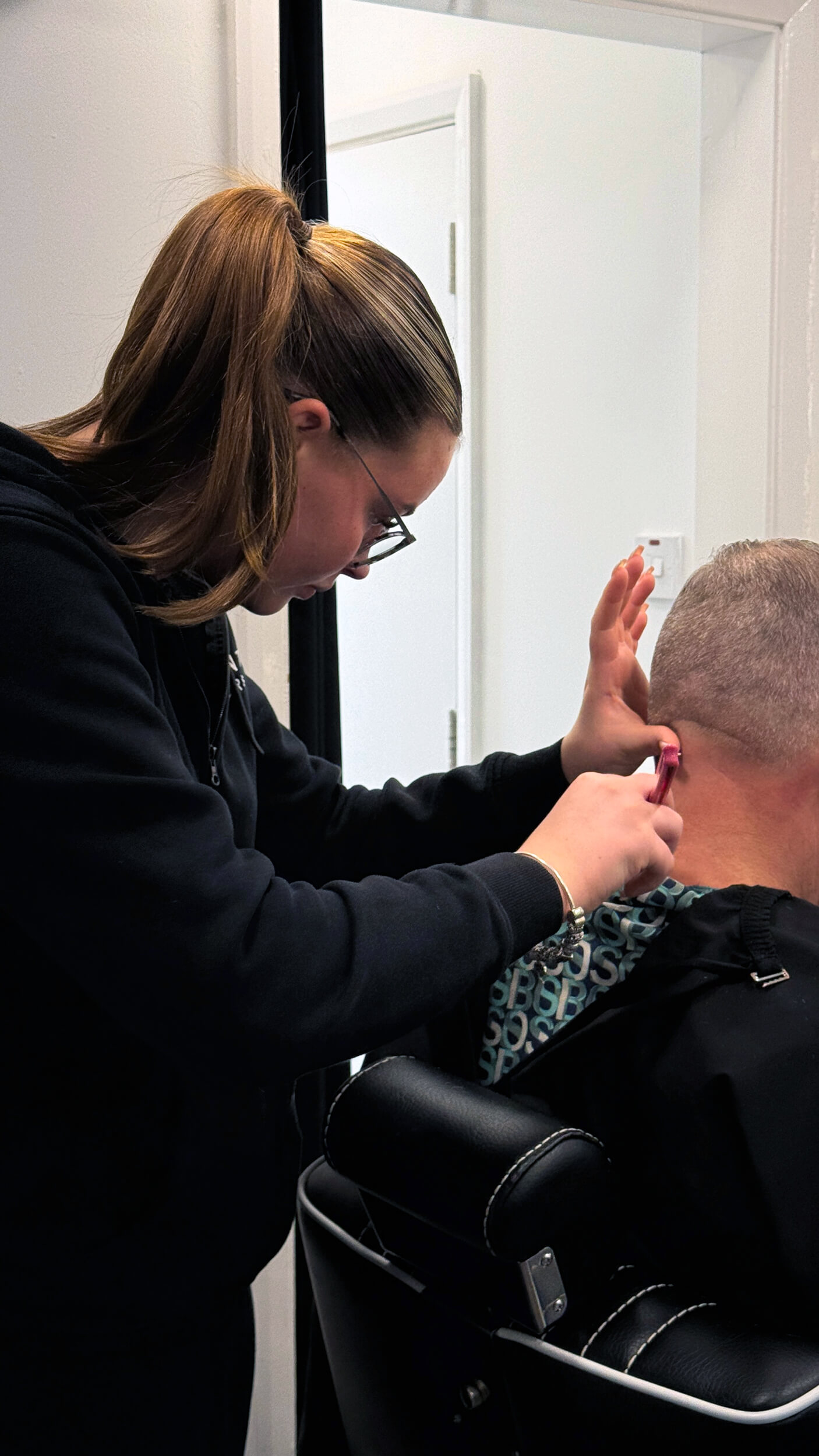 Hair stylist using a cut throat razor on the back of a man's neck