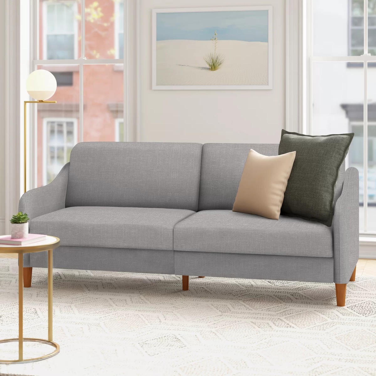 Gray sleeper sofa with decorative pillows in a light-filled room