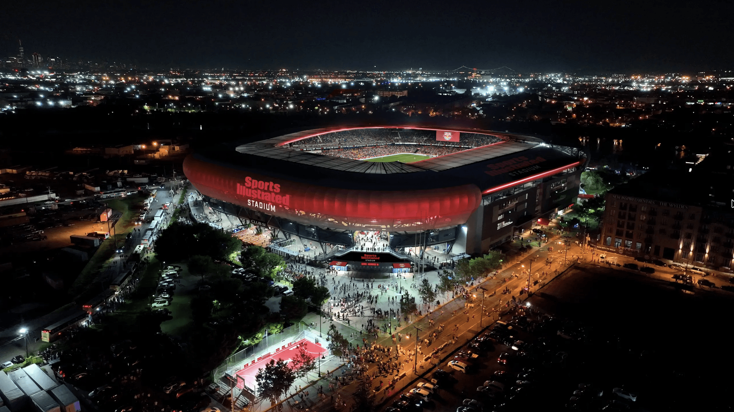 Close-up portrait of a person wearing a gray insulated hooded jacket with the hood up, showing their face framed by the hood against a light background.