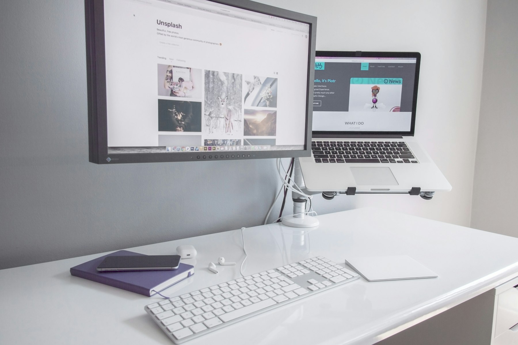 Website design shown on a monitor and laptop on a white desk