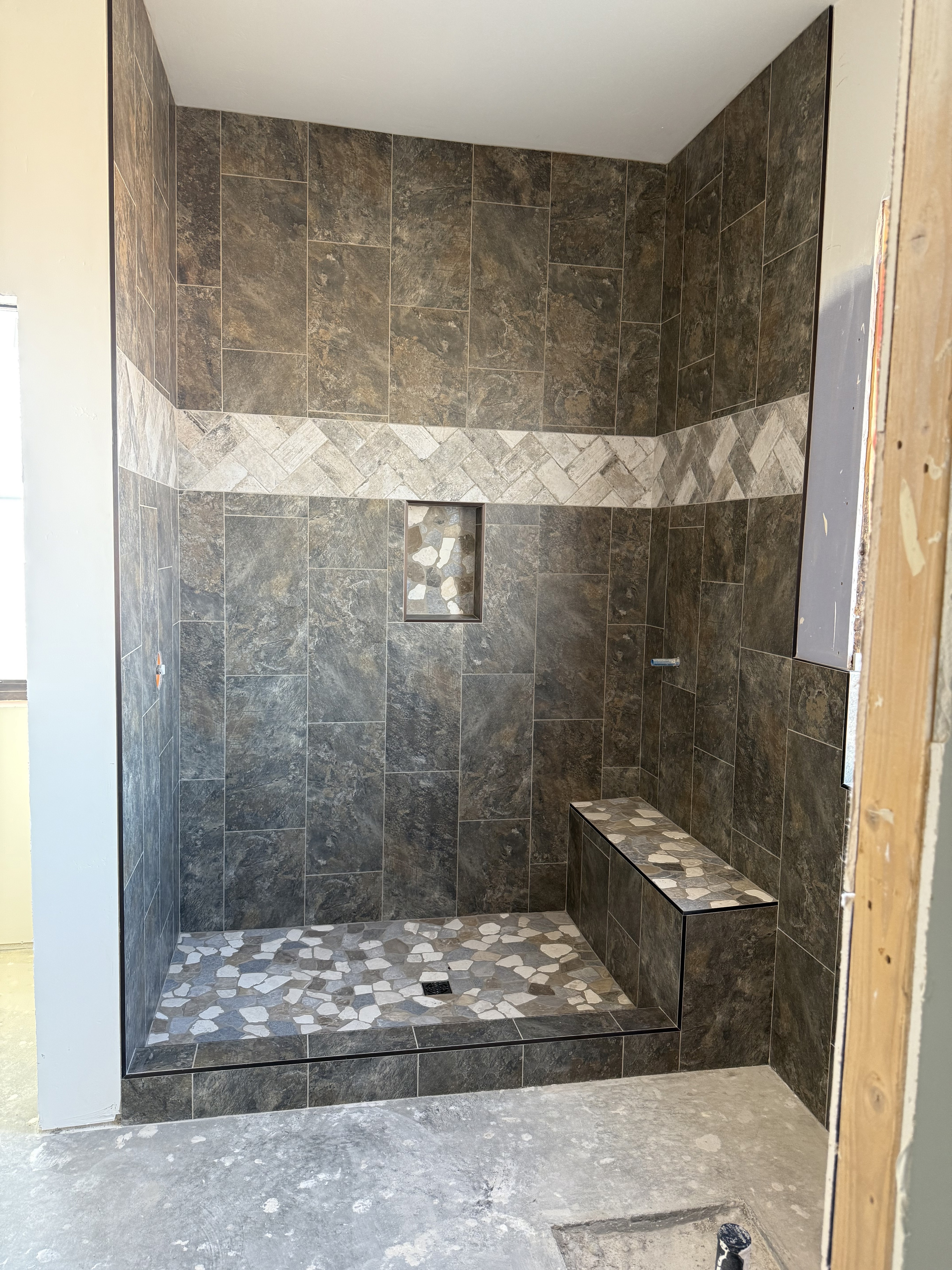 Luxurious bathroom vanity area with a dramatic wall featuring large format natural stone tiles in varying earthy tones and complex veining, serving as a striking backsplash above a double sink vanity.