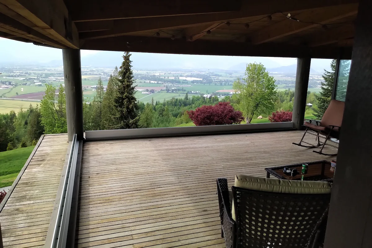 Spacious wood deck with semi-frameless glass railings and a panoramic valley view in Agassiz, BC.