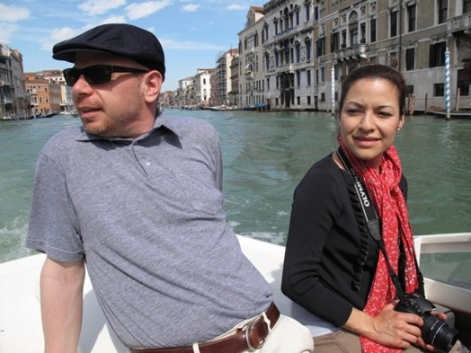 A photo of two people surfing the Venice channels in a boat.