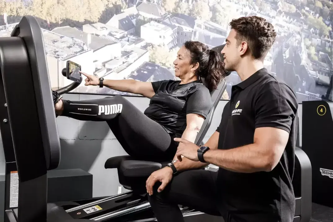 A man and woman are exercising on rowing machines in a gym, focused on their workouts.