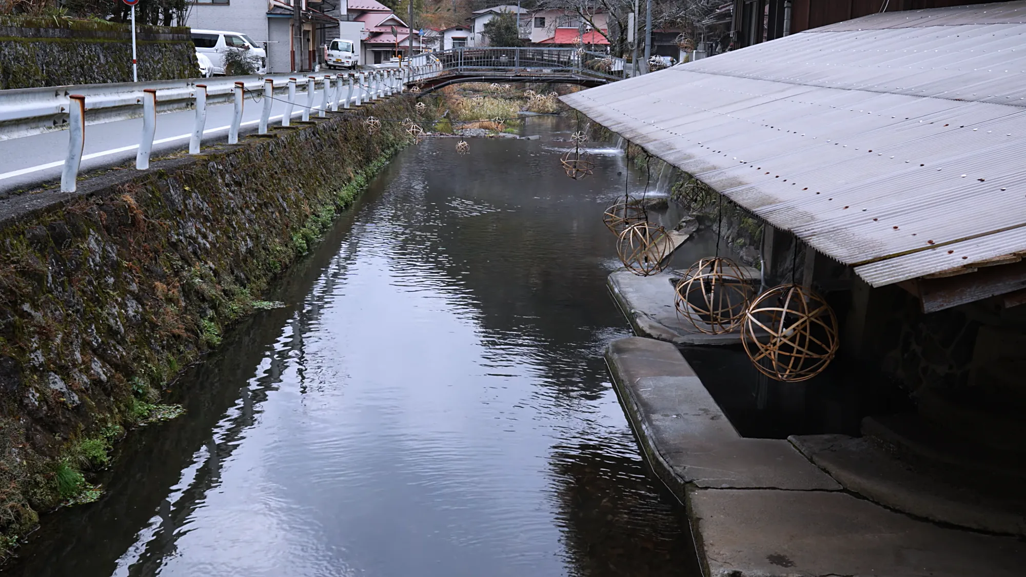 The river at Kurokawa Onsen running between the guardrail road and the covered walkway