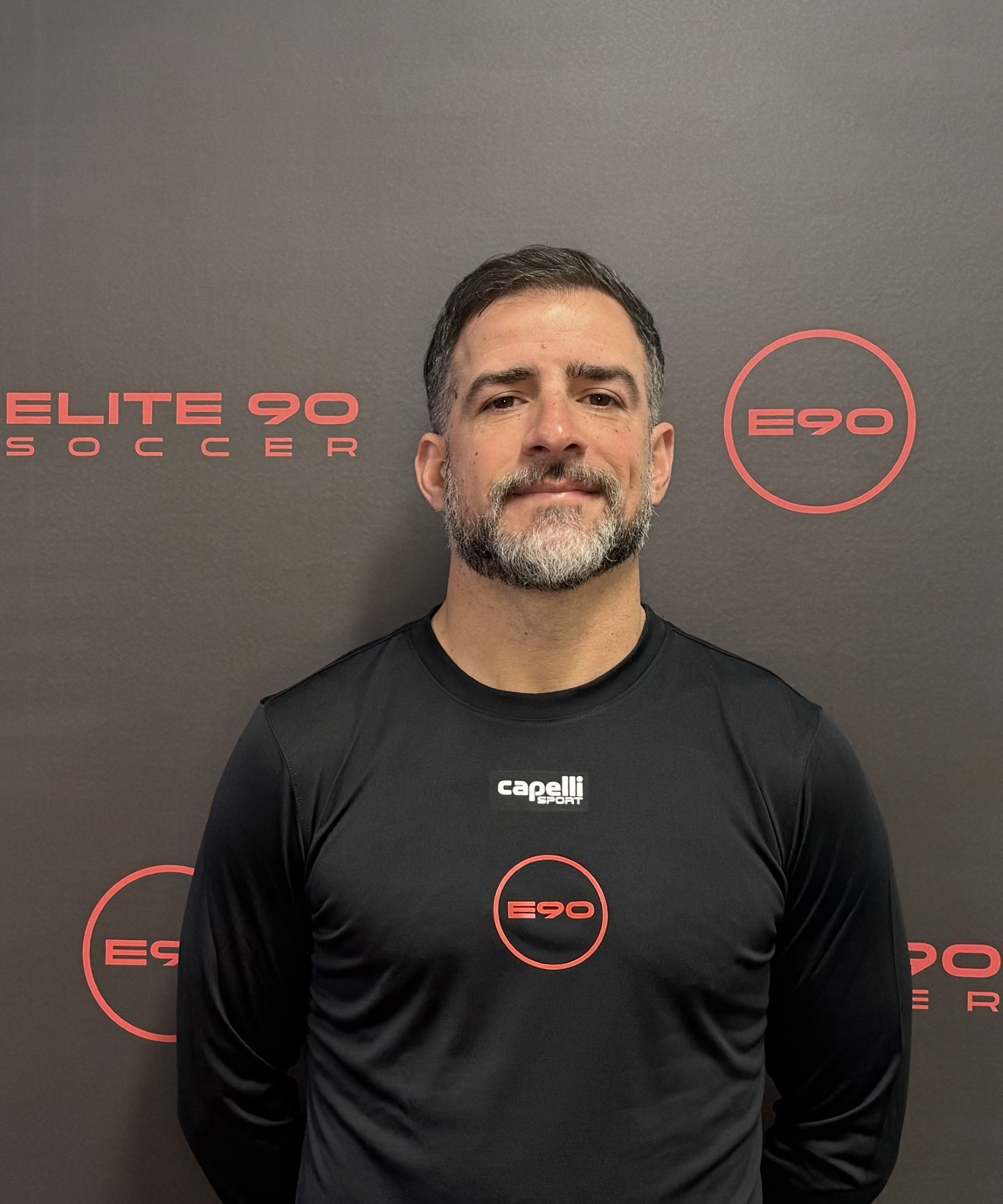 A stylish individual in a black shirt and silver pants stands against a blurred background, creating a dynamic and modern aesthetic.