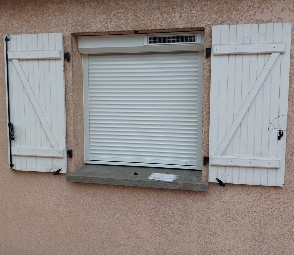 Fenêtre avec volet roulant blanc fermé et encadrement beige.